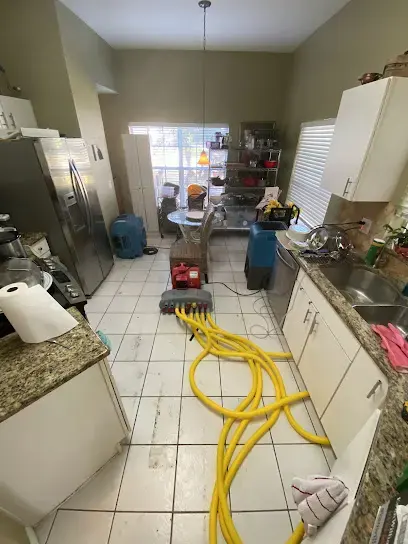 Extraction hoses and air movers set up across a tile kitchen floor in Plant City