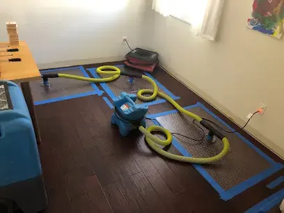 Floor drying mats and an air mover drying a hardwood floor to the S500 goal